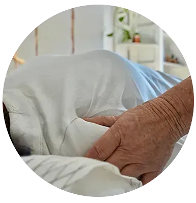 Una persona sostiene la mano de otra persona en una cama de hospital.