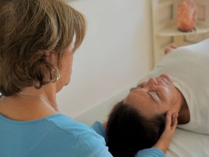 Una mujer con una camisa azul sostiene la cara de un niño.