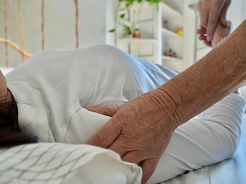 Una mujer con una camisa azul está parada frente a una escultura.